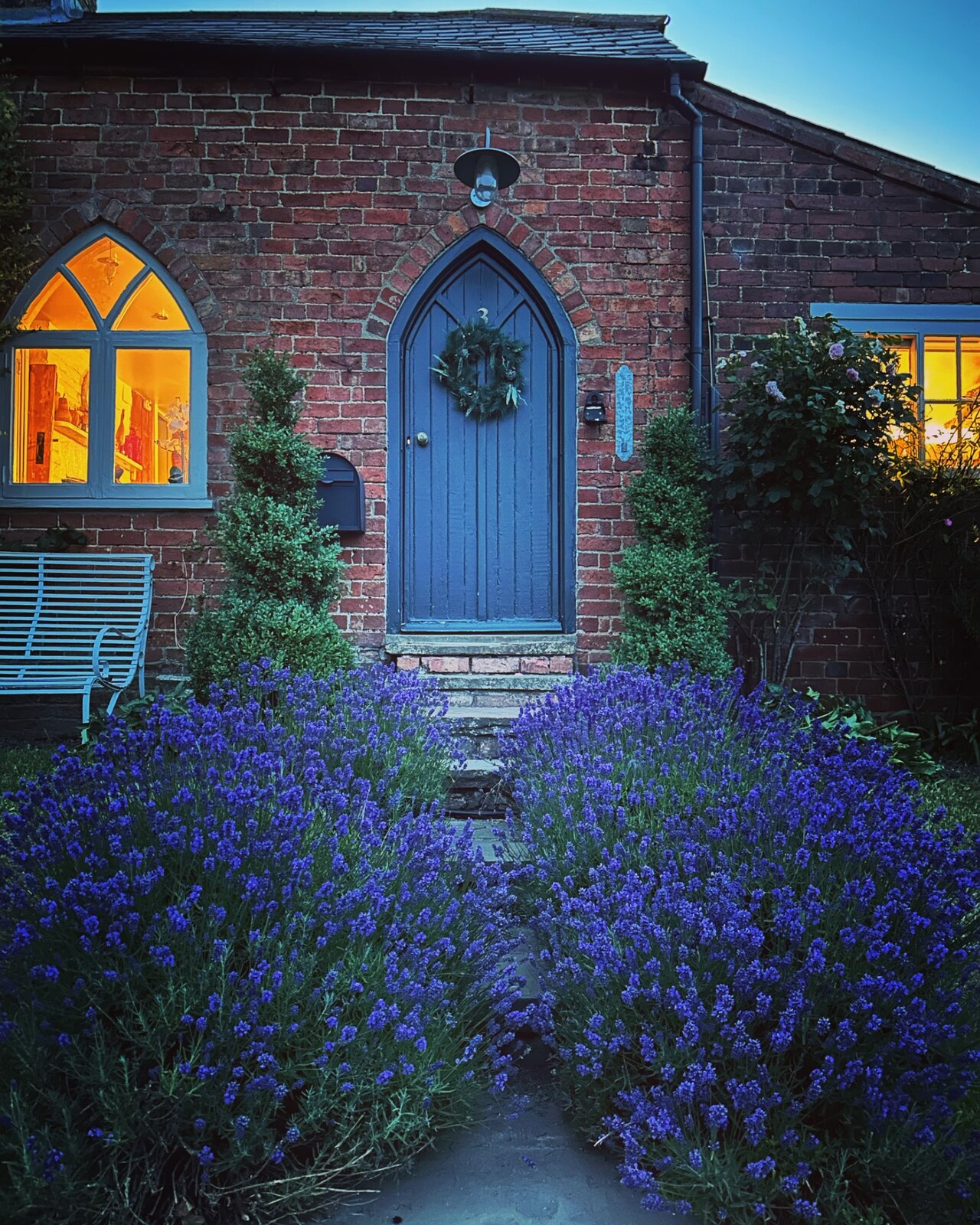 The front door of Jolls Cottage framed by lavender at dusk